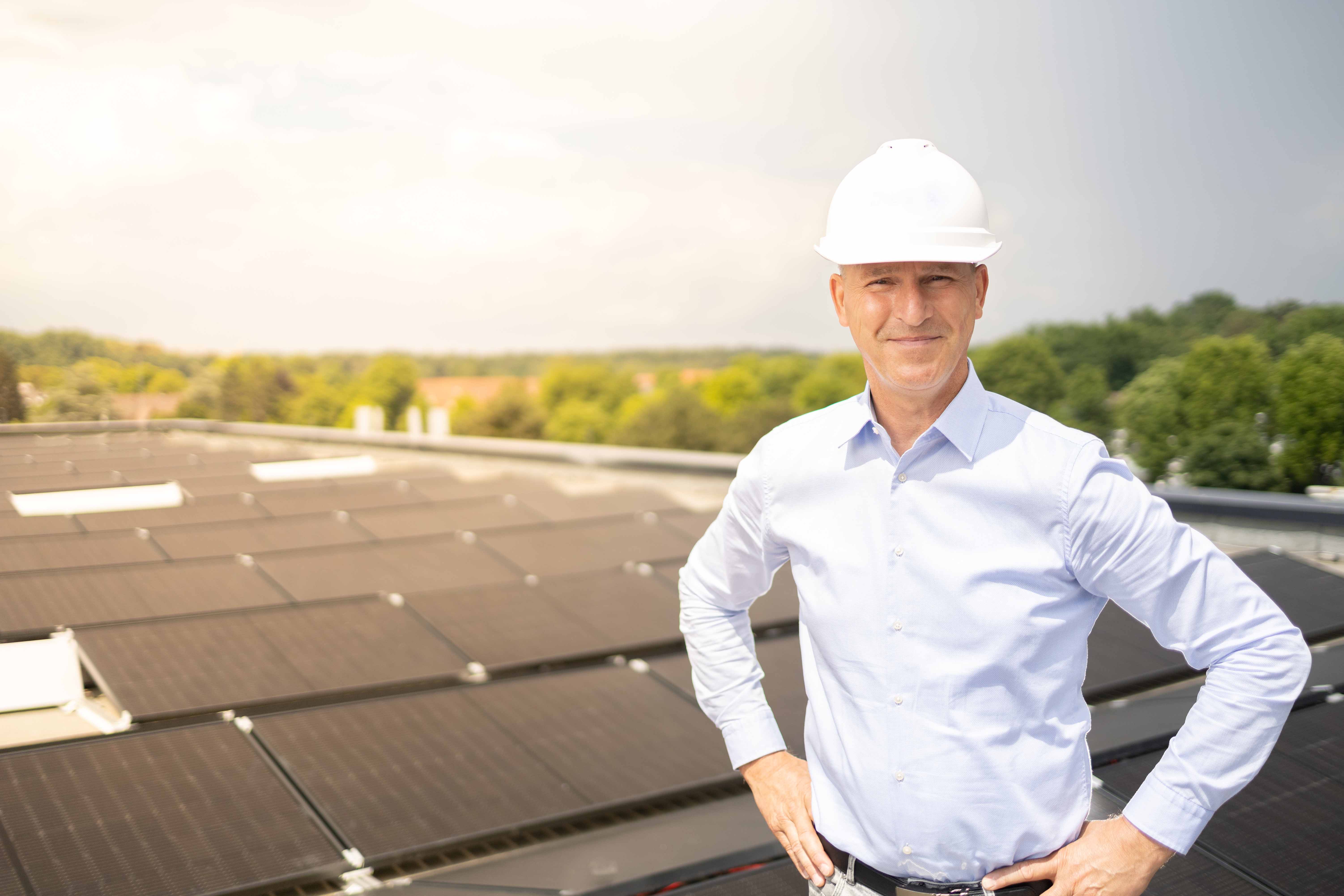 Bernd Becker steht stolz auf dem Dach des Instituts. Im Hintergrund befinden sich Solarpanele.