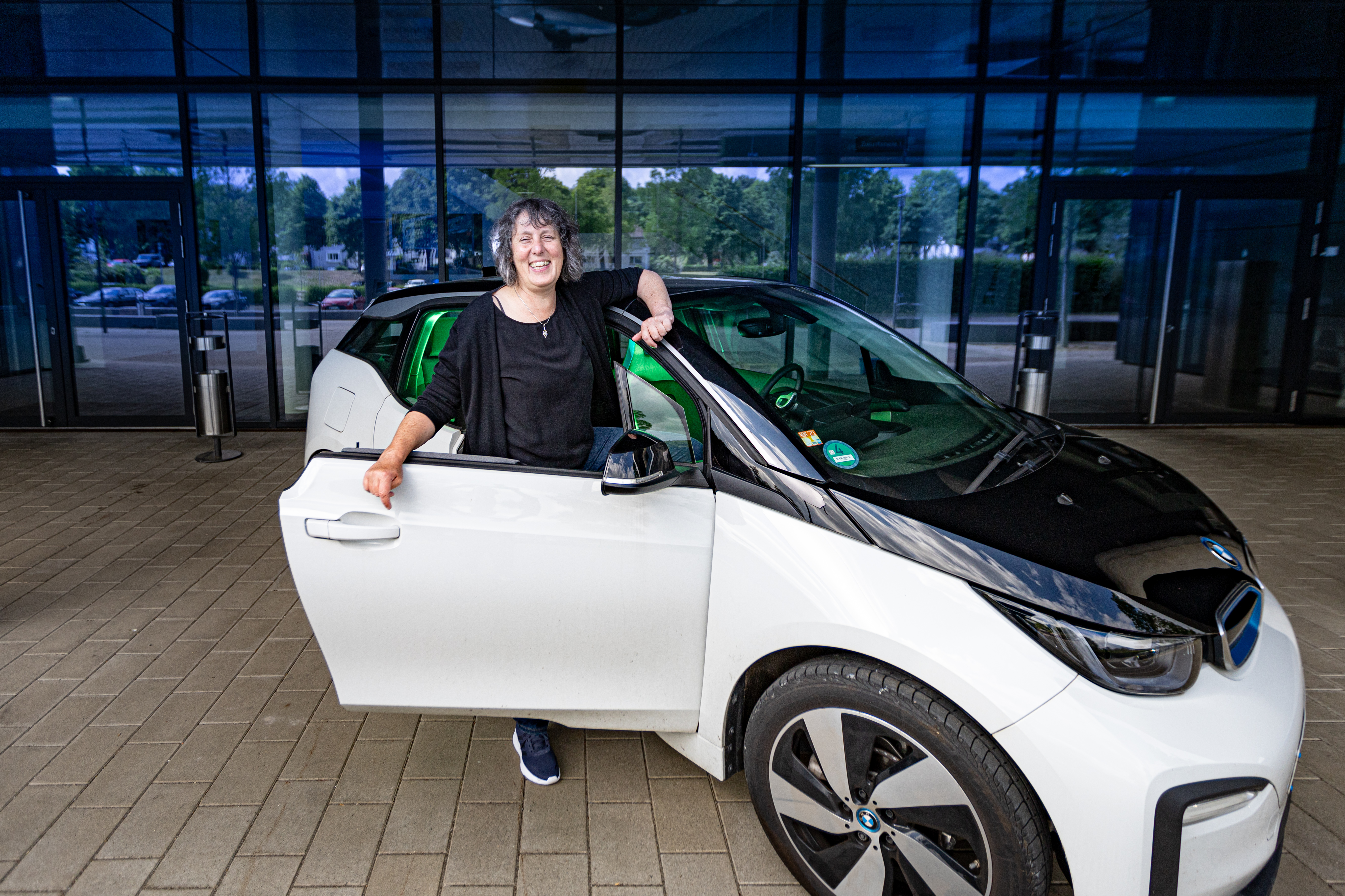 Angelika Surkamer steht mit einem Elektroauto von BMW vor dem Eingang des Fraunhofer IEM.