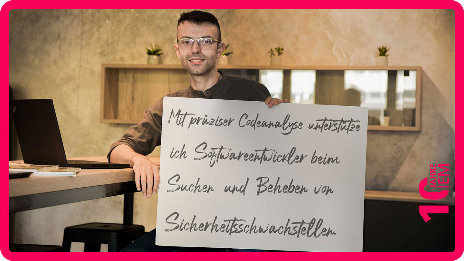 Goran Piskachev sitzt mit einem Schild in der Hand am Schreibtisch. Auf dem Schild steht sein EinSatz.