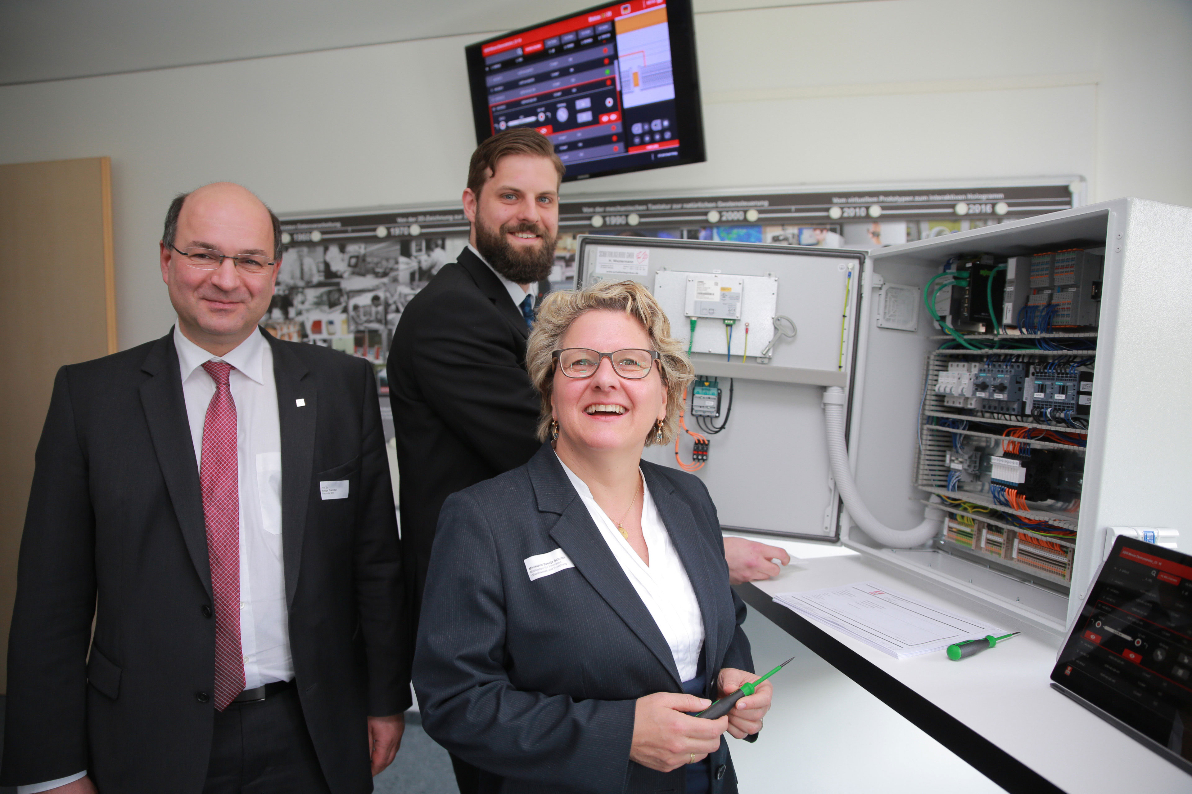 Zeigen NRW-Wissenschaftsministerin Svenja Schulze eine digitale Montageanleitung für einen Schaltschrank: Prof. Ansgar Trächtler (Leiter Fraunhofer IEM, links) und Matthias Greinert (Wissenschaftler am Fraunhofer IEM).