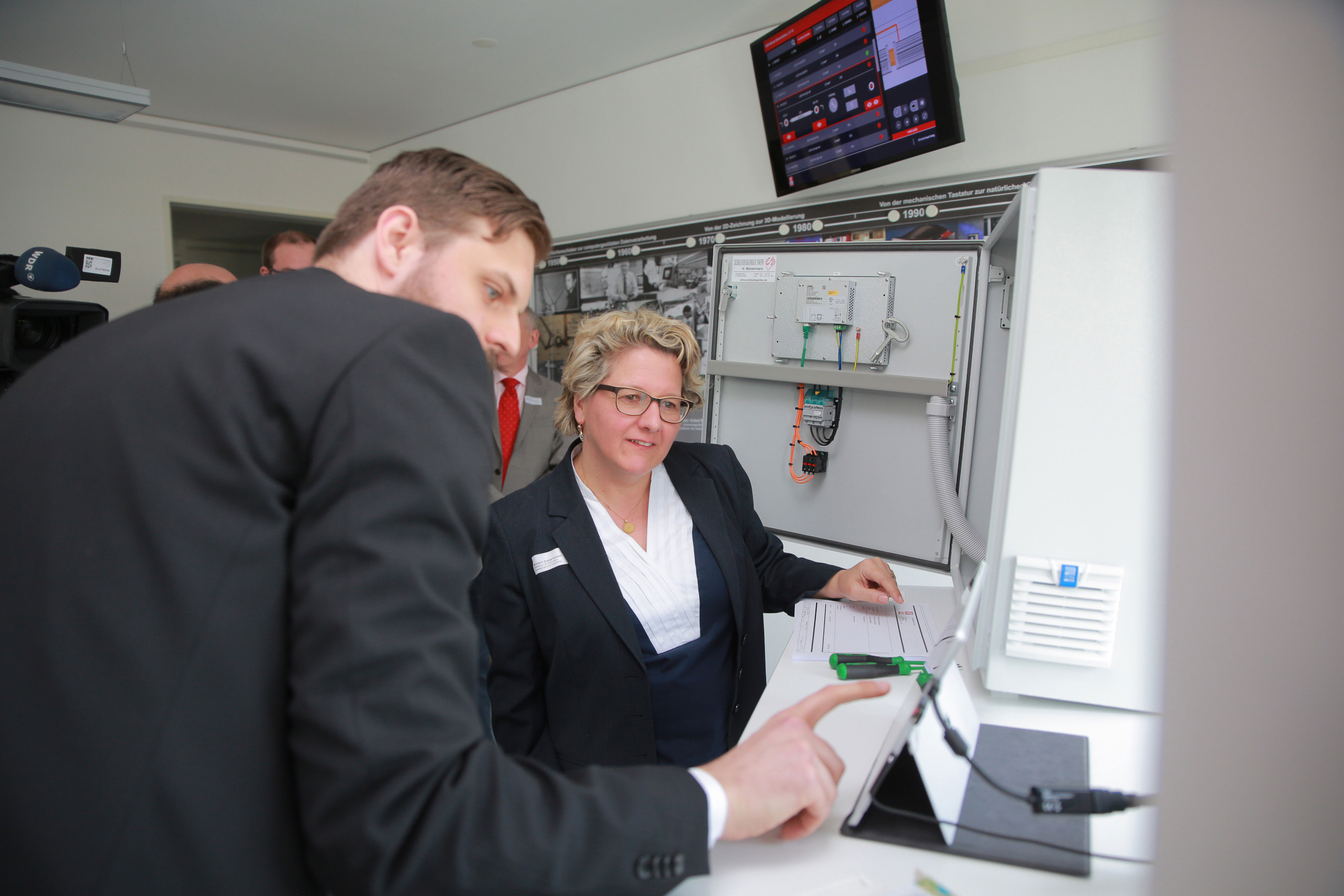 Matthias Greinert (Wissenschaftler am Fraunhofer IEM) zeigt NRW-Wissenschaftsministerin Svenja Schulze eine digitale Montageanleitung für einen Schaltschrank.
