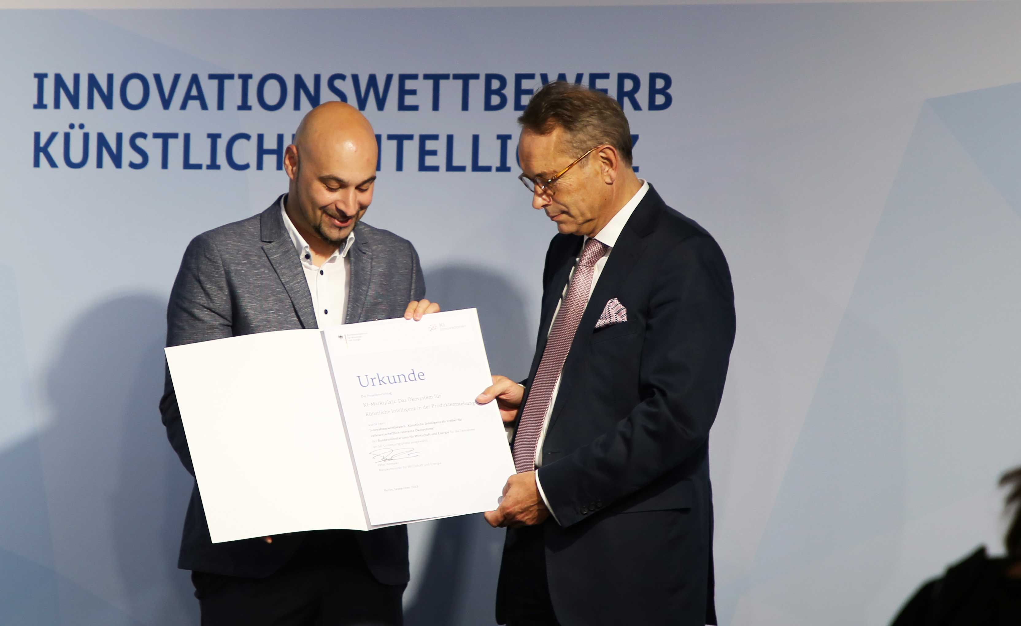 Prof. Roman Dumitrescu (Vorstand Heinz Nixdorf Institut, Direktor Fraunhofer IEM und Geschäftsführer it´s OWL) nimmt die Förderzusage für den KI-Marktplatz von BMWi-Staatssekretär Dr. Ulrich Nussbaum entgegen. Prof. Roman Dumitrescu (Vorstand Heinz Nixdorf Institut, Direktor Fraunhofer IEM und Geschäftsführer it´s OWL) nimmt die Förderzusage für den KI-Marktplatz von BMWi-Staatssekretär Dr. Ulrich Nussbaum entgegen.