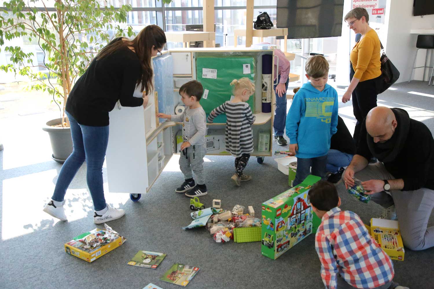 Mitarbeiterinnen und Mitarbeiter mit ihren Kindern beim »Unboxing« der KidsBox.