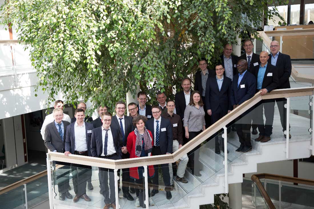 Gruppenfoto mit Frauen und Männern, die nebeneinander und hintereinander auf einer Treppe stehen.