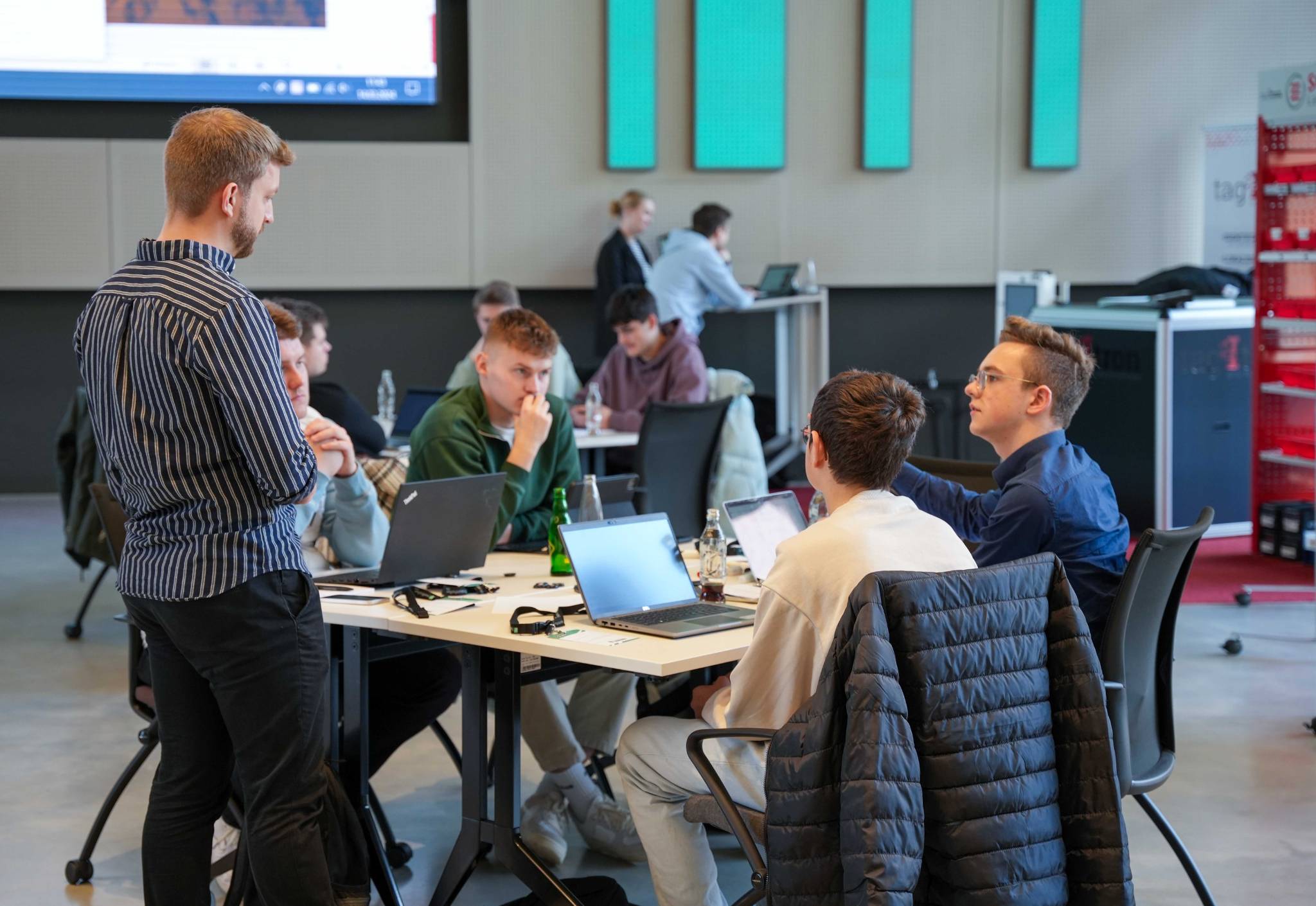 News Azubi Makeathon IoT Ein Mitarbeiter im Gespräch mit 4 Jungs