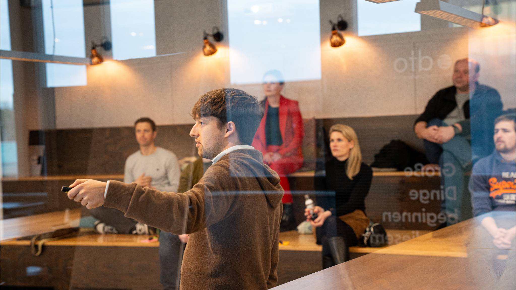 News Digital Maker Workshop Fünf Personen sitzen auf einer Tribüne und hören jemanden zu.