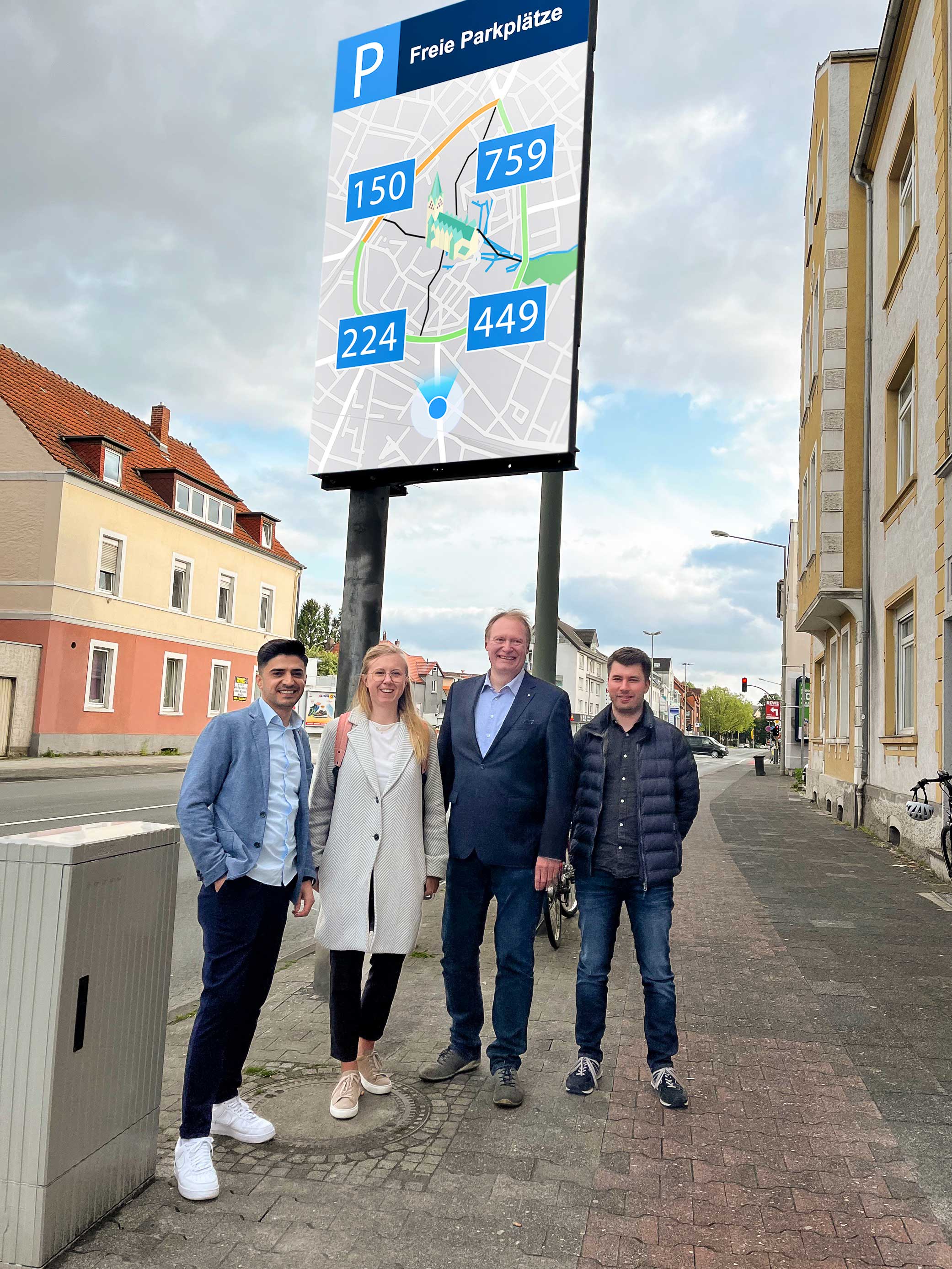 Gruppe steht vor digitalem Parkleitsystem.