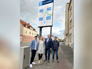 Gruppe steht vor digitalem Parkleitsystem.