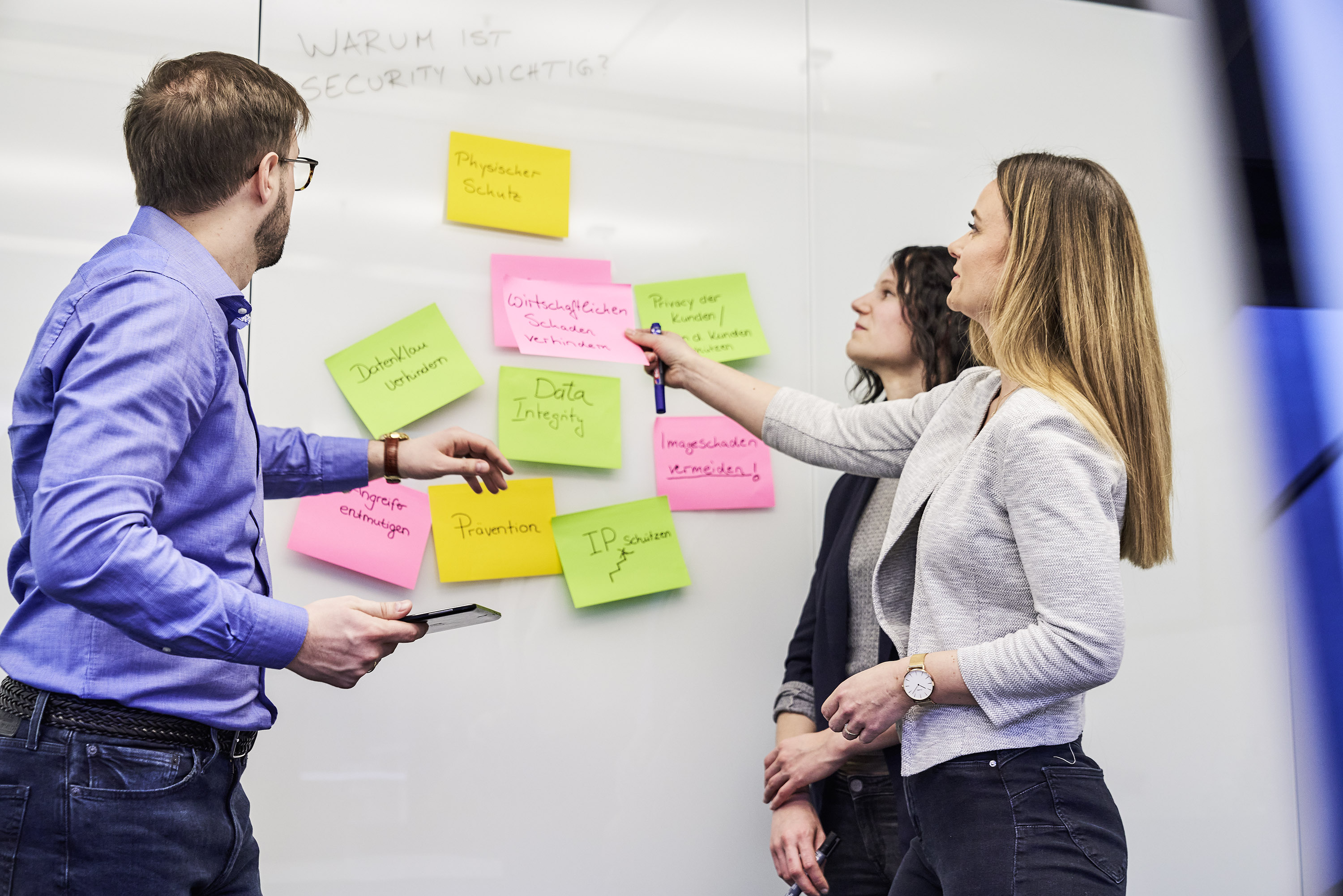 Engineering der Zukunft Newsletter Drei Personen die vor einem Whiteboard stehen und über Post-its reden