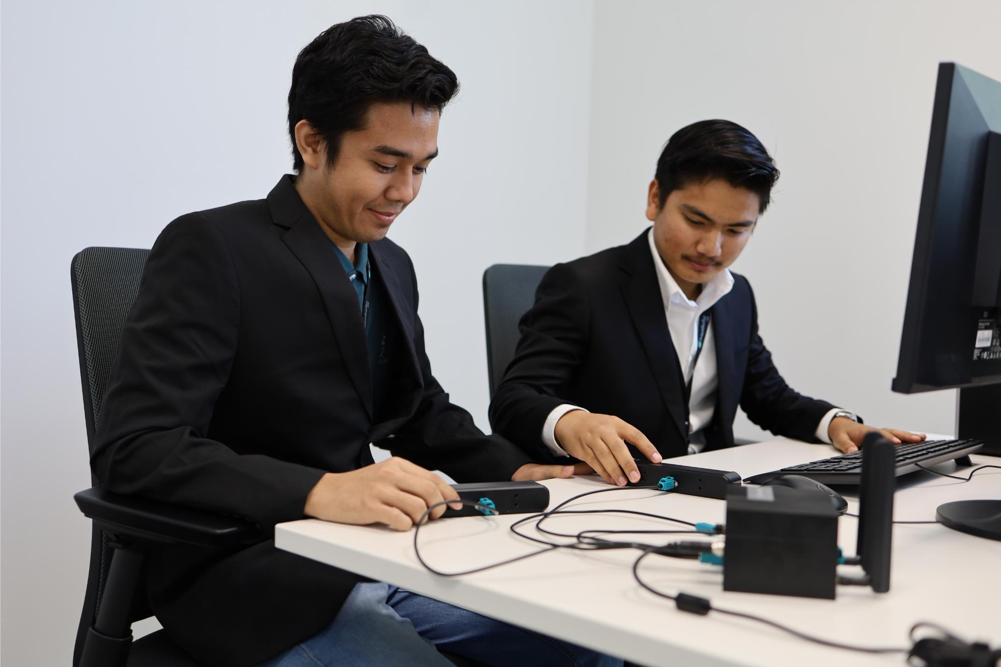 Praktikanten arbeiten gemeinsam an einem Computer.