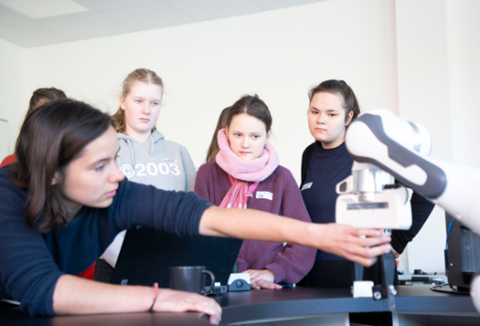 News Girls Day Gruppe von Mädchen steht an Roboterarm.