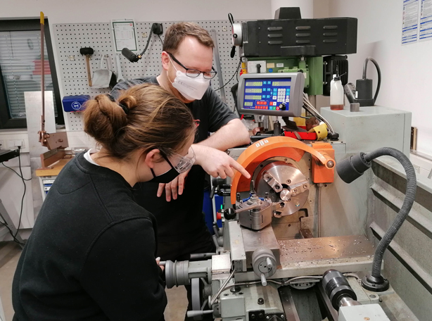 News Betriebspraktikum Sabine Ein Mann erklärt einem Mädchen eine Maschine.