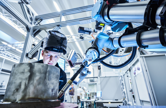 News Kollaboratives Schweißen Mann bedient Roboter-Schweißarm.