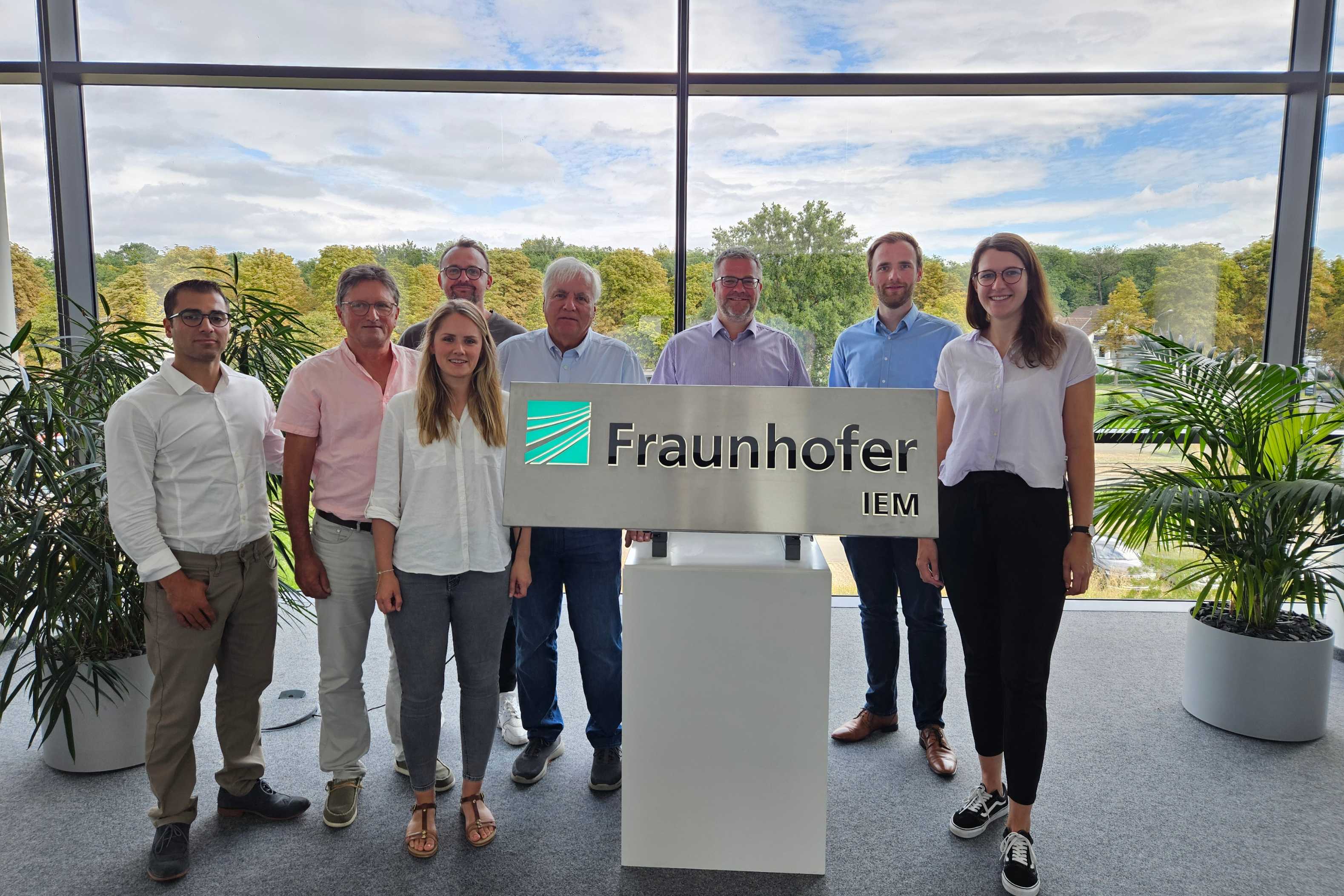 Projekt NitroChar Menschen vor dem Fraunhofer IEM Logo.