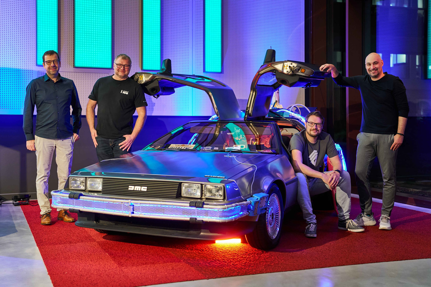 DeLorean mit Podcastern die daneben stehen.