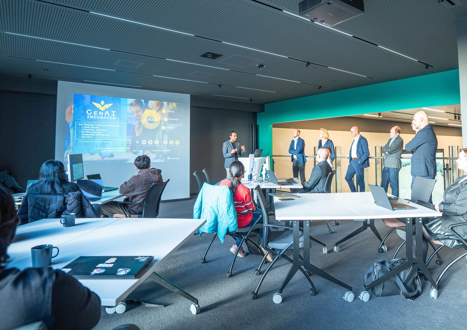 News GenAI Incubator Laban Asmar hält eine Präsentation vor Gruppe.