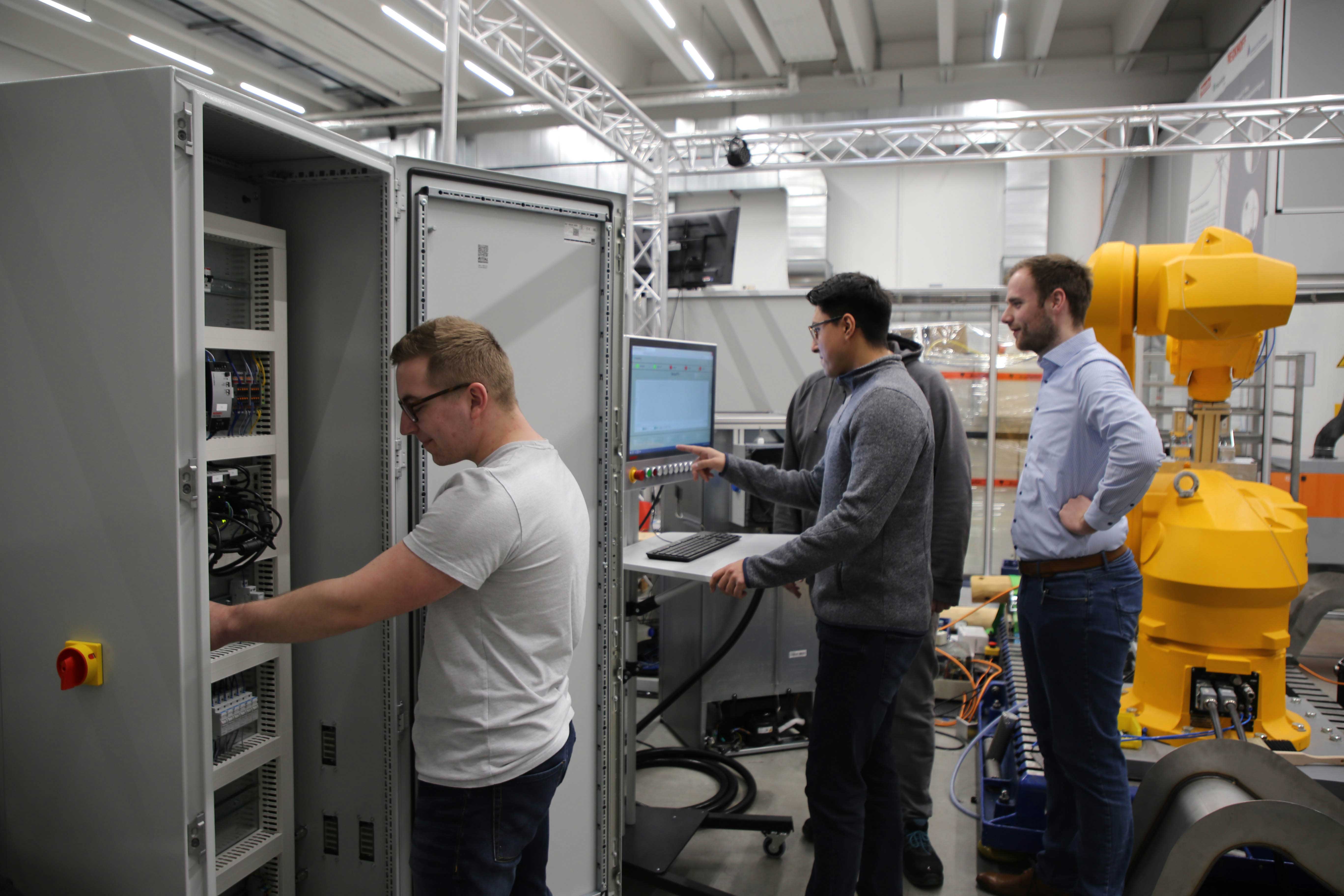 Praktikantenteam entwickelt innovative Energiekonzepte Praktikanten stehen am Prüfstand.