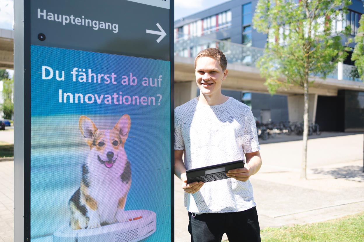 News FSJ Johannes FSJler Johannes Siebert steht neben einem digitalen Panel.