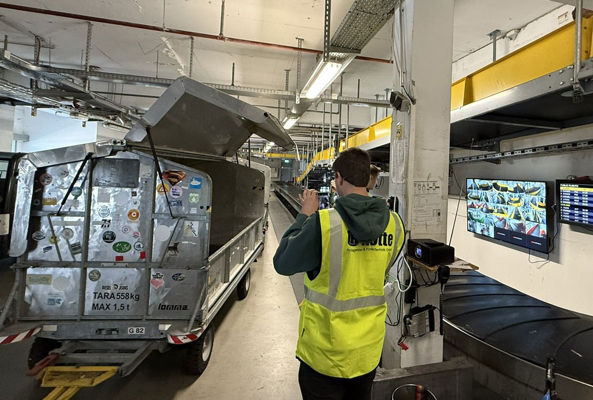 Projektstart AG für NBA Mitarbeiter steht vor Container und Gepäckband.