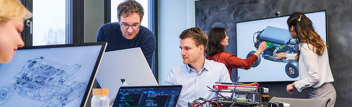 Vier Personen im SE Live Lab, von denen sich zwei Frauen über ein CAD-Modell austauschen.