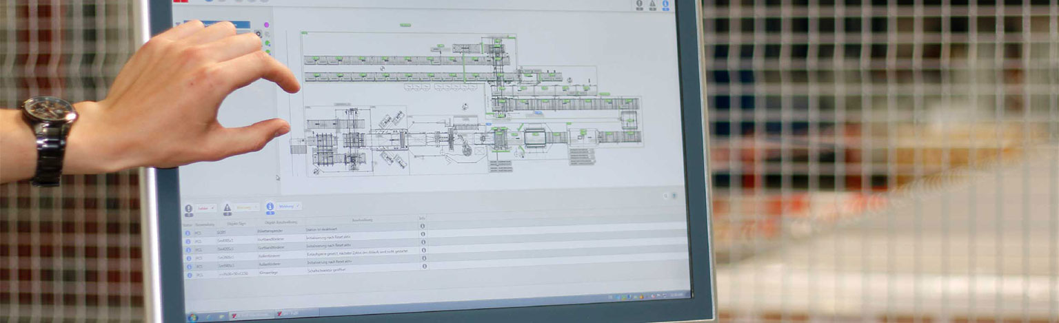 Tablet in einer Industriehalle zeigt den Bauplan einer Maschine, eine Hand zeigt darauf.