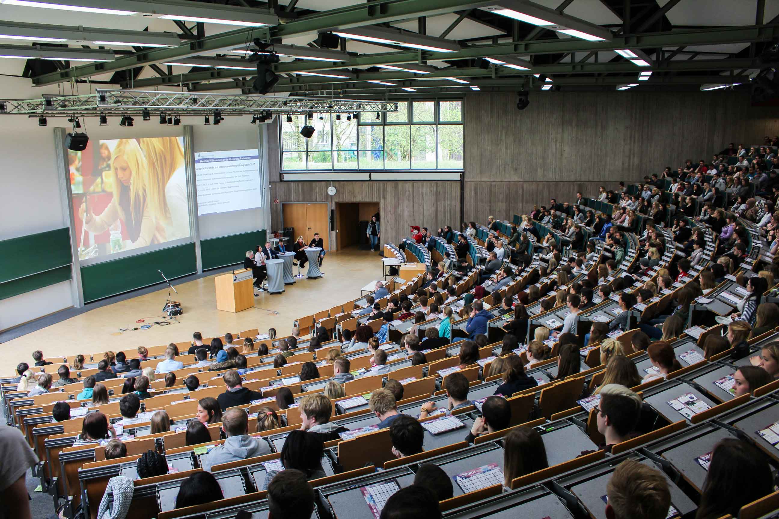 Lecture hall of a university with many students sitting on rows of benches