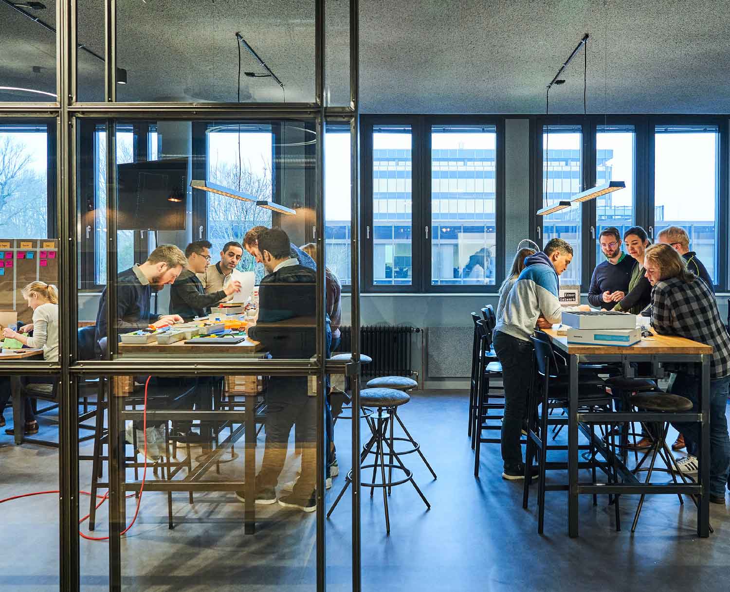 Room with large tables where many people stand and work together in a workshop