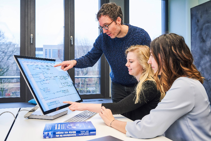 Two women and a man discuss new ideas on a computer.